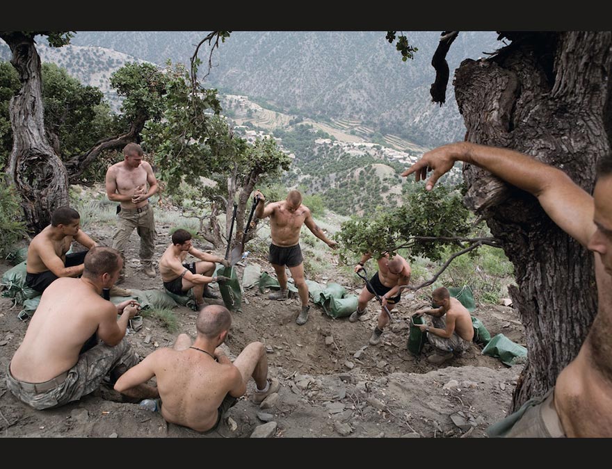 Bare-chested men digging in the earth for sandbags