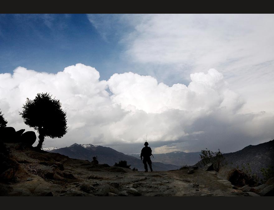 Man silhouetted against a landscape with a tree and clouds