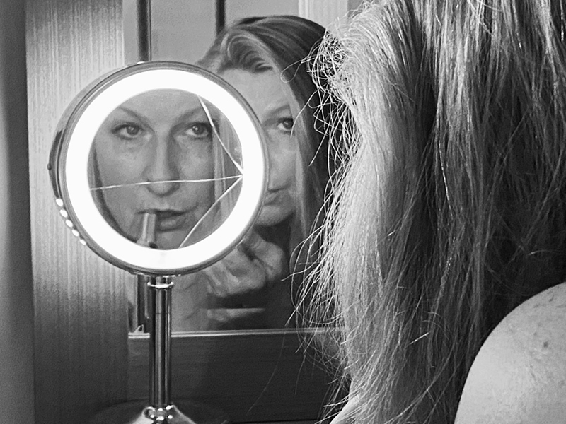 black and white photo of a young woman looking into a series of mirrors