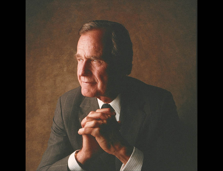 Man in a suit with this hands clasped in front of him