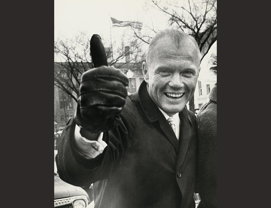 Black and white photo of a man in a suit with his thumb up