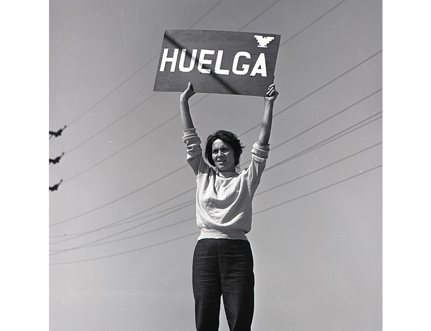 Woman holding a sign above her head that reads" STRIKE" in Spanish