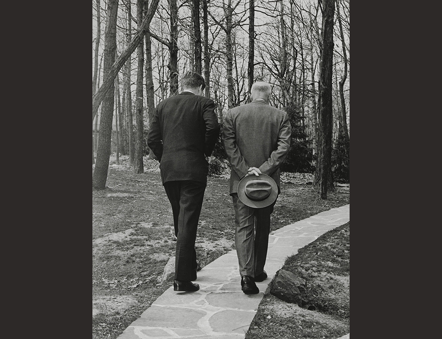 Two men with backs to camera walking in the woods