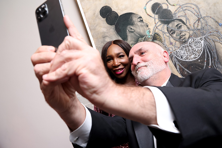 older man and a young Black woman taking selfies