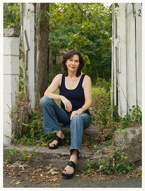 full length photo of a darhk haired woman seated on steps