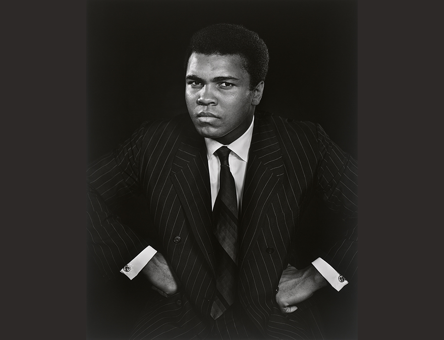 African American man in a suit staring directly at the camera with his hands on his hips