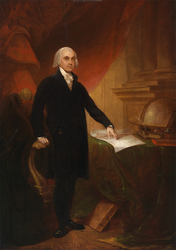 man in black coat and stockings standing near a table