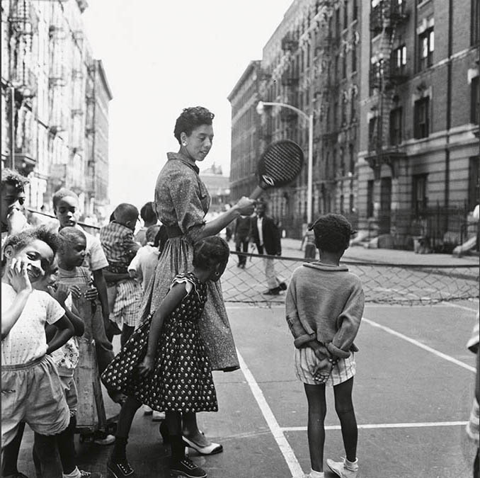 young woman on a street talking to children