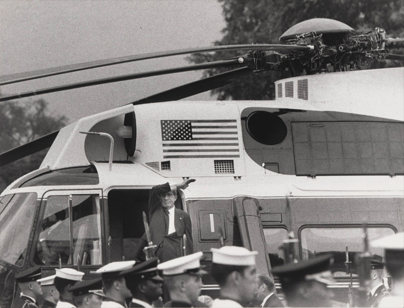 man climbing aboard a helicopter waving to a crowd