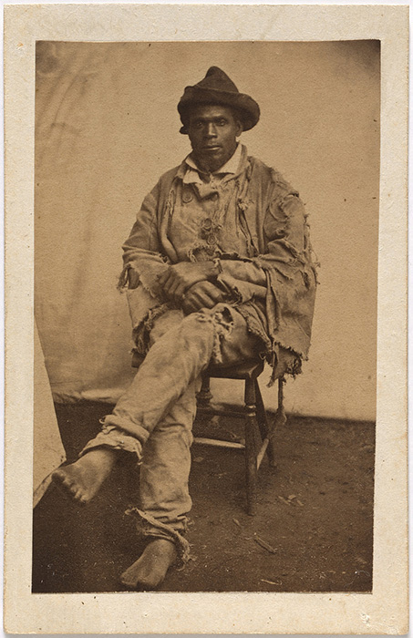 full length portrait of a Black man in ragged clothes and bare feet