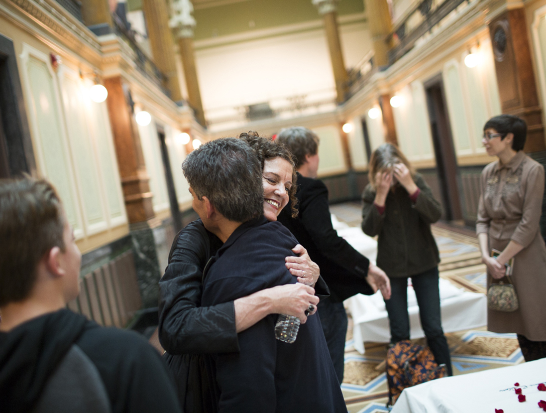 Visitors vieweing the cots and rosepetals as part of the installation