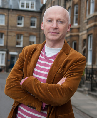 Bald man in a brown blazer and a pink striped sweater