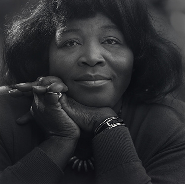 close-up photo of a Black woman with her chin resting on her hands