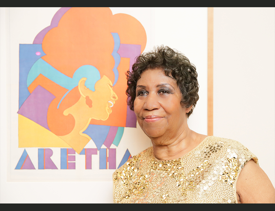 Woman in a  sequinned dress standing beside a graphical poster of herself
