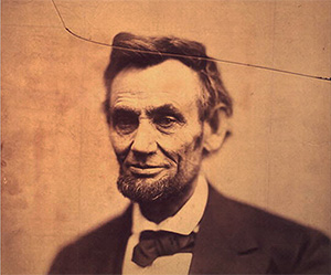 sepia tinted photo of a bearded man in a black suit