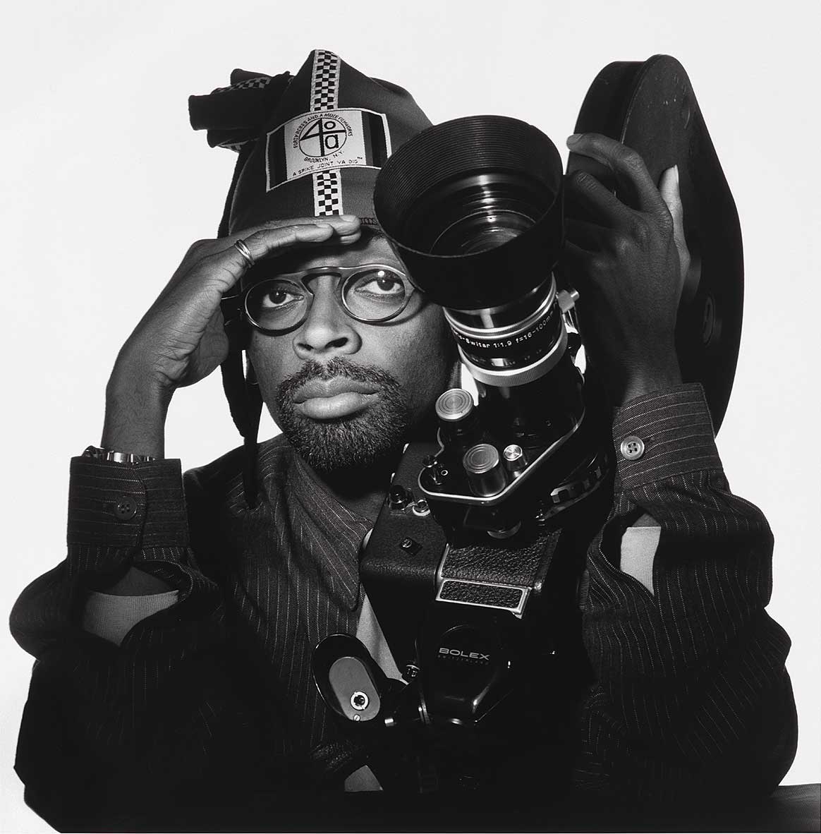 Black and white photograph of a man staring at the viewer with his face behind a camera