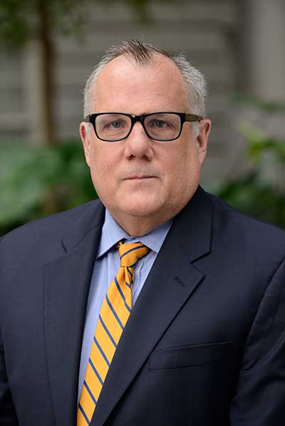 Man with short gray hair and horn-rimmed glasses