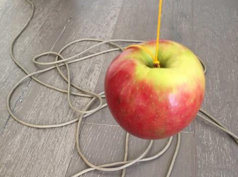 Red and yellow apple suspended by a string