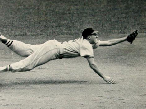 Black and white photo of Brooks Robinson diving for a ball, his body horizontal to the ground