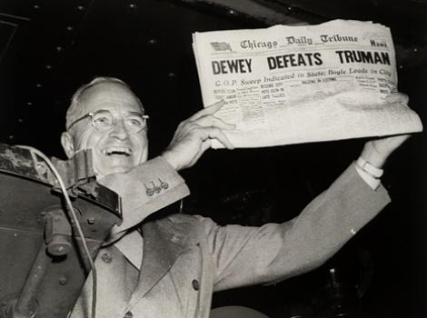 Black and white photo of Harry Truman holding newspaper with headline "Dewey Defeats Truman"