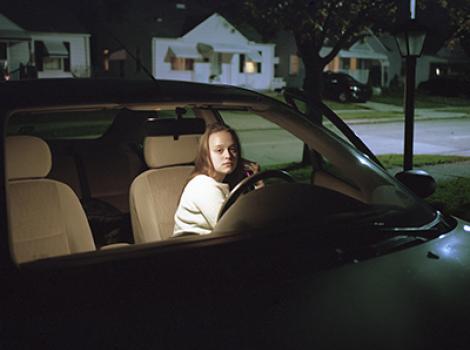 Young girl talking on her phone in the driver's seat of a car
