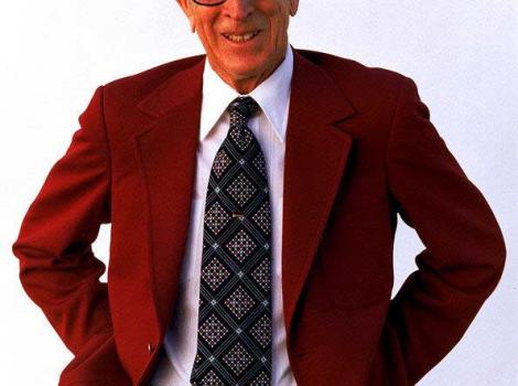 Photograph portrait of John Wooden, in red suit and patterned tie