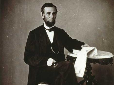 Black and white photograph portrait of Abraham Lincoln, in formal clothing and bowtie, sitting down