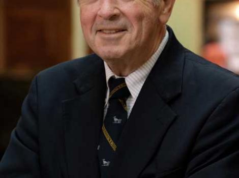 Color photo from the waist up of Martin Sullivan in a blue suit jacket and multi-color tie, standing inside the National Portrait Gallery.