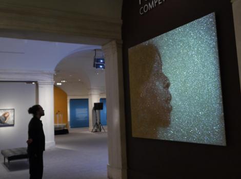 Museum visitor looking at projection portrait 