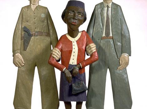 Painted wooden sculpture of a handcuffed Rosa Parks being arrested by two white police officers
