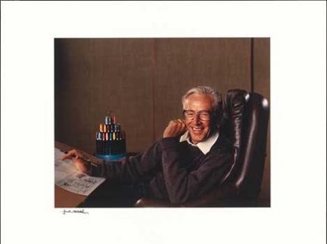 Photograph of Charles Schulz in chair, smiling, and with art materials
