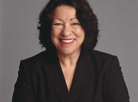Sonia Sotomayor in black formal shirt and with arms crossed, looking straight into camera smiling