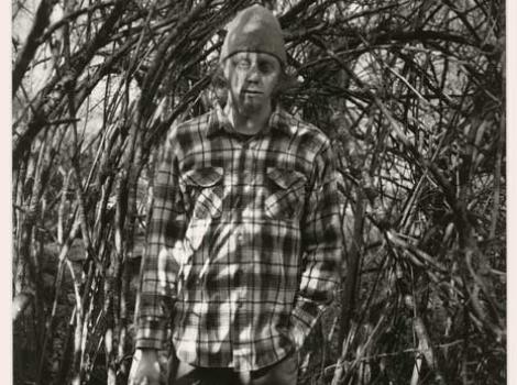 Black and white photo of man in plaid shirt in forest
