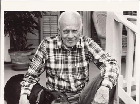 Black and white photo of Walker Percy on porch steps with two dogs