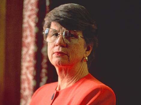 A woman in three-quarter view crossing her arms and looking straight into the camera