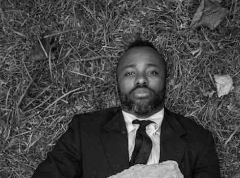 Black and white photo of a man buried under a rock and staring at the camera