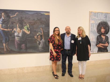 Three women standing in front of a painting