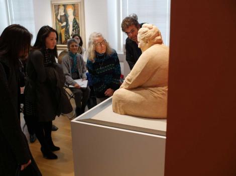 A group of people closely examining a sculpture in a museum gallery