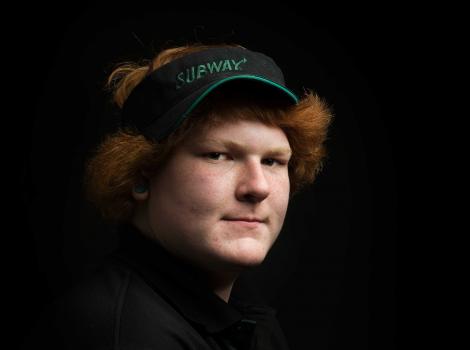 Photograph of a man against a black background wearing a food service uniform