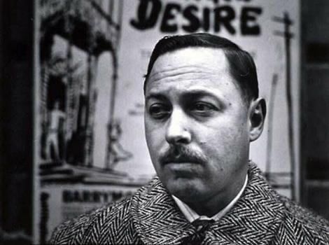 Black and white image of a man looking into the distance and standing in front of a sign that says "A Streetcar Named Desire"