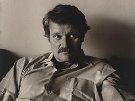 Seated man with dark hair and a moustache