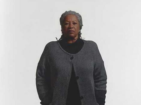 African American woman in a dark sweater standing against a white background