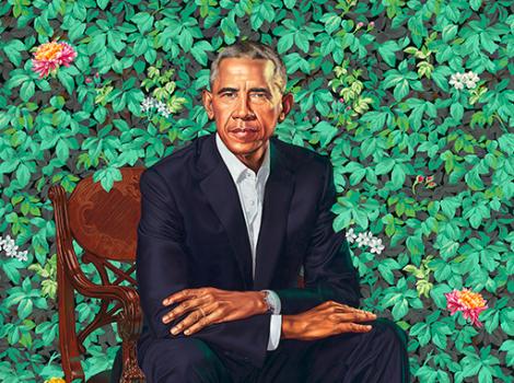President Barack Obama seated against green foliage