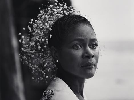 Bust length photo of a woman with baby's breath flowers in her hair.