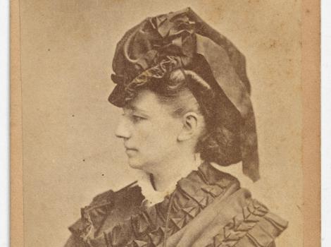 Black and white photo of a woman in profile with hat and gloves.