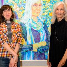 Two women standing in front of a portrait