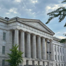 Photograph of the National Portrait Gallery's exterior against a blue sky and clouds with its central columns in the center.