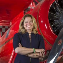 Woman in black standing in front of a red plane