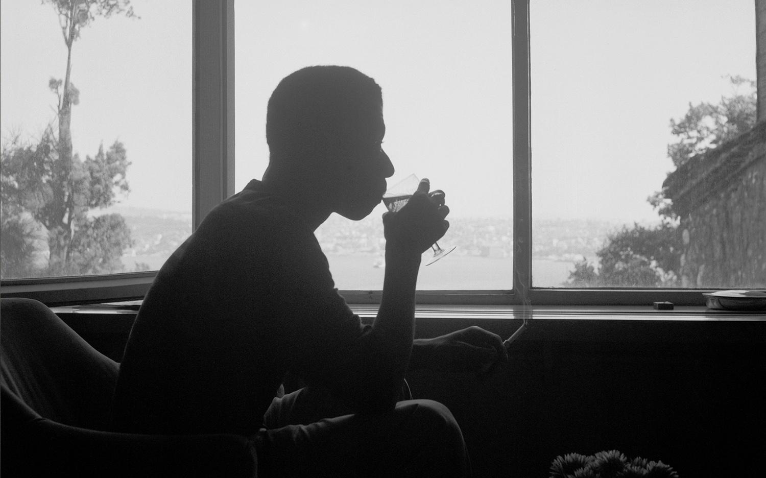 silhouette fo a man in a window drinking from a glass