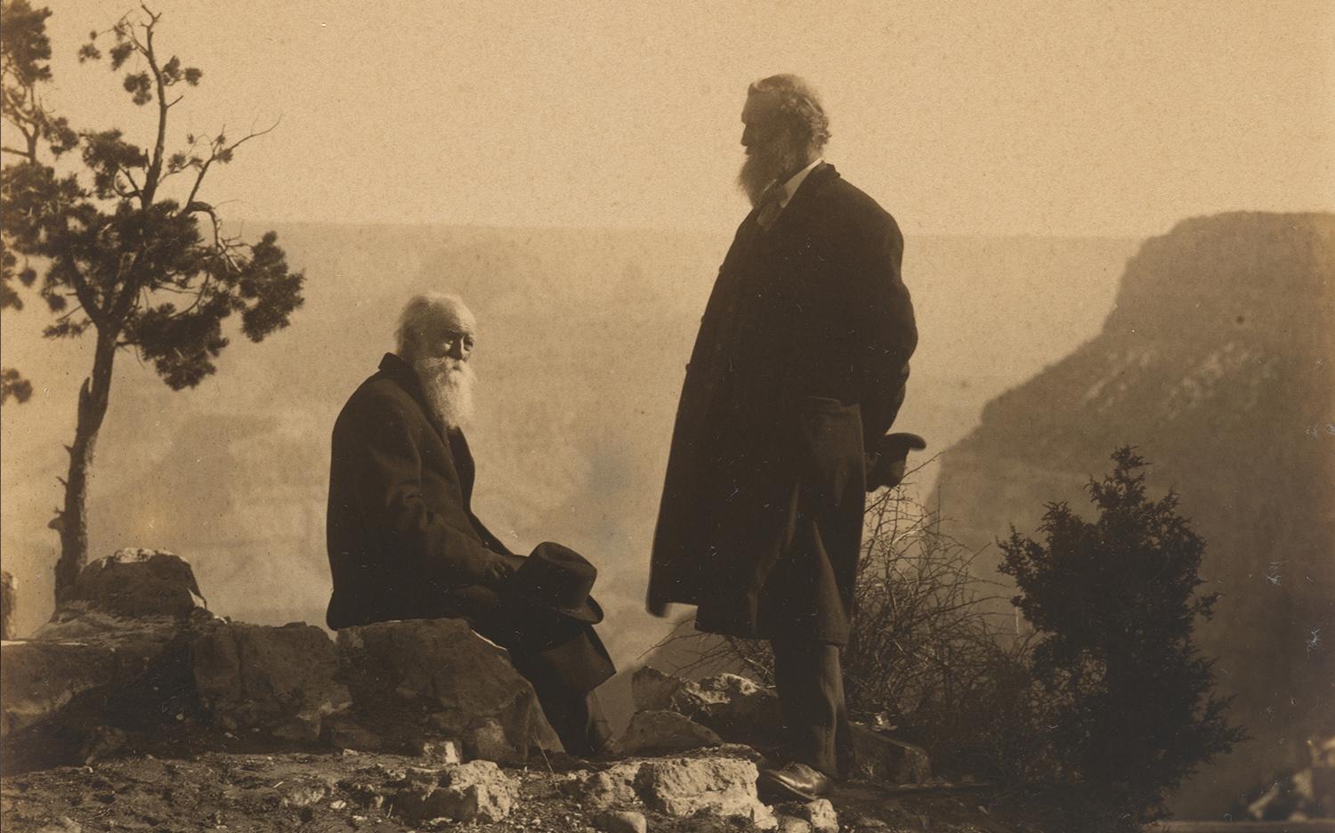sepia-tinted photo of two men standing on a mountaintop